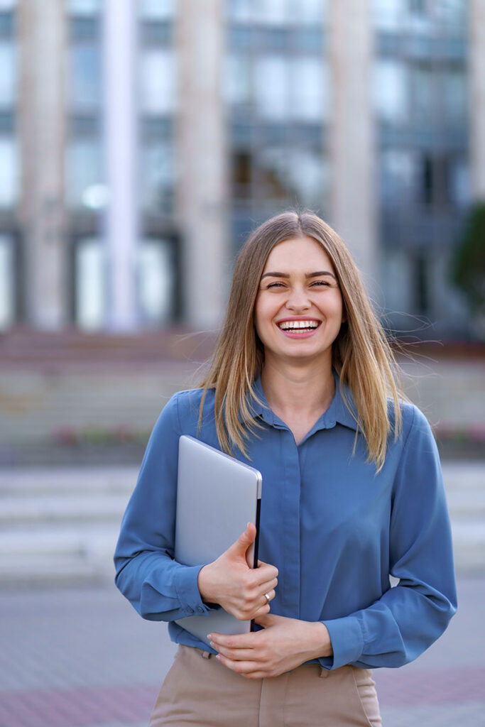 Portrait smiling woman holding laptop outdoors